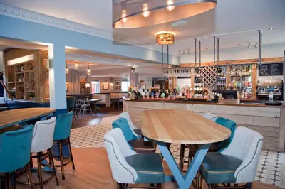 a restaurant with tables and chairs and a bar at The Royal Hotel in Bolton le Sands