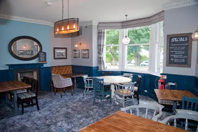 a restaurant with blue walls and tables and chairs at The Royal Hotel in Bolton le Sands
