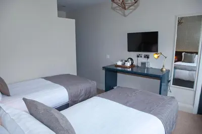 a hotel room with two beds and a desk with a tv at The Royal Hotel in Bolton le Sands