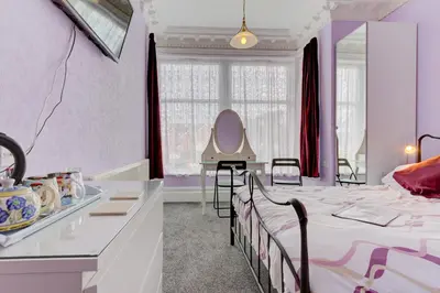 a room with a bed and a table with a mirror at The Claremont in Lytham St Annes