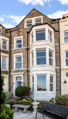 a large brick building with a bench in front of it at The Broadwater Guest House in Morecambe
