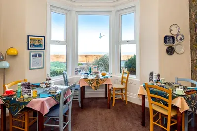 a dining room with tables and chairs and windows at The Broadwater Guest House in Morecambe
