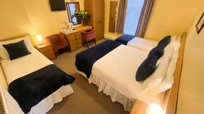 a hotel room with two beds and a desk at Sutcliffe Hotel in Blackpool