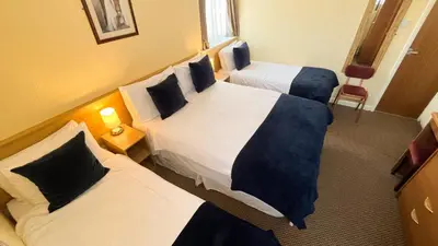 a hotel room with two beds and two chairs at Sutcliffe Hotel in Blackpool