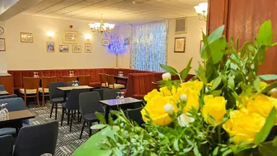 a dining room with tables and chairs and yellow flowers at Sutcliffe Hotel in Blackpool