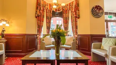 a living room with a vase of flowers on a table at Sutcliffe Hotel in Blackpool