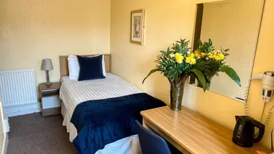a room with a bed and a vase of flowers on a table at Sutcliffe Hotel in Blackpool