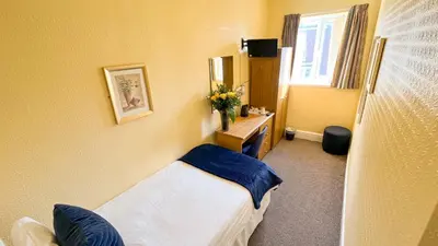 a bedroom with a bed and a desk and a mirror at Sutcliffe Hotel in Blackpool