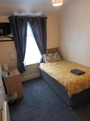 a small bedroom with a bed and a window at Strides Hotel in Blackpool