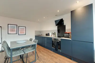 a kitchen with blue cabinets and a table and chairs at Mathew Street City Centre Apartments by Happy Days in Liverpool