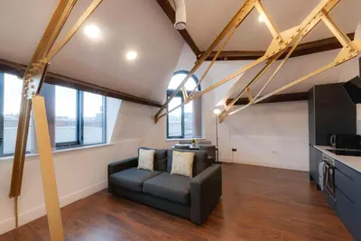 a living room with a couch and some windows at Mathew Street City Centre Apartments by Happy Days in Liverpool