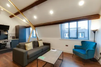 a living room with a couch and a blue chair at Mathew Street City Centre Apartments by Happy Days in Liverpool