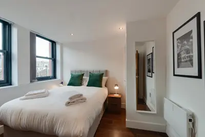 a bedroom with a large white bed with green pillows at Mathew Street City Centre Apartments by Happy Days in Liverpool
