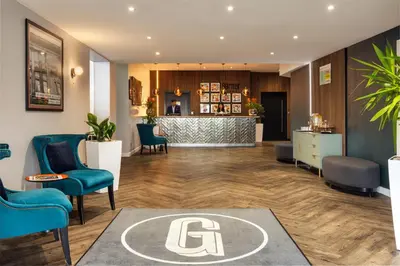a lobby with blue chairs and a bar at Garner Hotel Preston Samlesbury by IHG in Preston