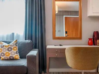 a living room with a blue couch and a mirror at Garner Hotel Preston Samlesbury by IHG in Preston