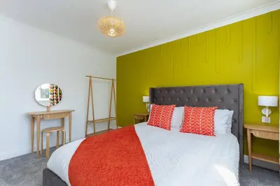 a bedroom with a bed with a green wall at Avella by the Park in Lytham St Annes