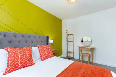 a bedroom with a bed with a green accent wall at Avella by the Park in Lytham St Annes