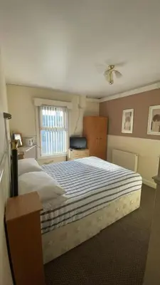 a bedroom with a large bed with a striped blanket at White Moon Hotel in Blackpool