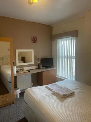 a bedroom with a bed and a desk with a mirror at White Moon Hotel in Blackpool