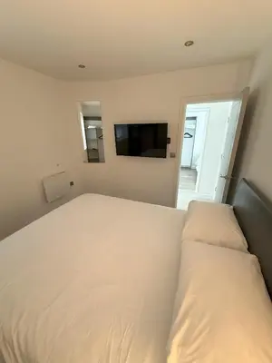 a bedroom with a white bed and a flat screen tv at Coastal Plaza in Blackpool
