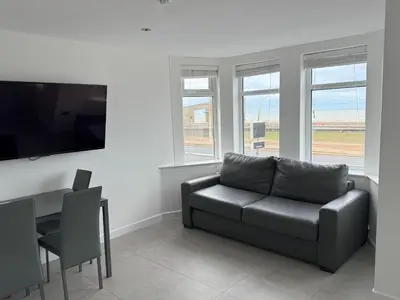 a living room with a couch and a table and windows at Coastal Plaza in Blackpool