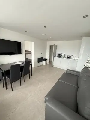 a living room with a couch and a table and a kitchen at Coastal Plaza in Blackpool