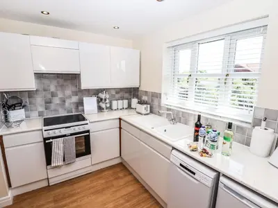 a white kitchen with white cabinets and a window at 3 Rothbury Place in Lytham St Annes