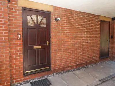 a brown door on a brick wall with a sidewalk at 3 Rothbury Place in Lytham St Annes