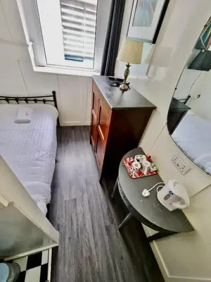 a small bedroom with a bed and a desk with a table at Elmora House in Blackpool