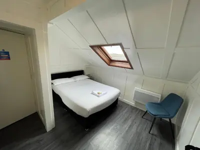 a small bedroom with a bed and a blue chair at Elmora House in Blackpool