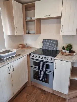 a kitchen with a stove and white cabinets at elbry in Heysham