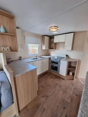 a kitchen with white cabinets and a sink and a stove at elbry in Heysham