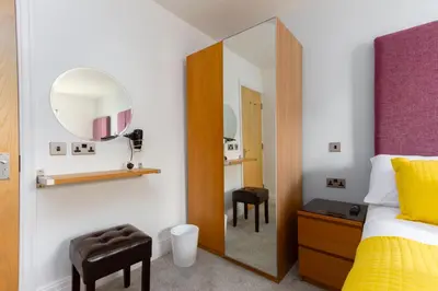 a bedroom with a mirror and a bed and stool at Granada Apartments Berkeley in Blackpool