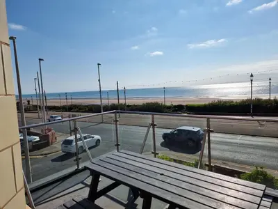 a wooden bench on a balcony with a view of the beach at Granada Apartments Berkeley in Blackpool