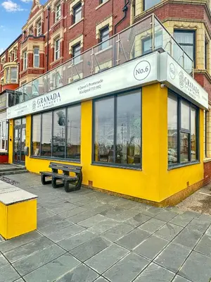 a yellow building with a bench in front of it at Granada Apartments Berkeley in Blackpool