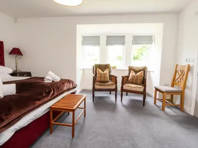 a bedroom with a bed and two chairs at Low Orchard House in Preston