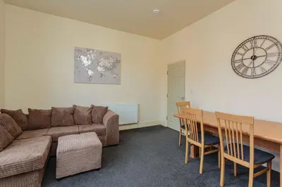 a living room with a couch and a table and a clock at Cherry Property - Coconut Suite in Blackpool