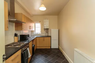 a kitchen with wooden cabinets and a white refrigerator at Cherry Property - Coconut Suite in Blackpool