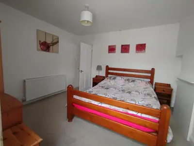 a bedroom with a wooden bed with pink sheets at Cosy end terrace in Lancaster