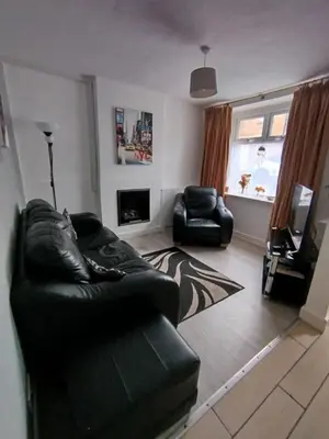 a living room with a black leather couch and a fireplace at Cosy end terrace in Lancaster