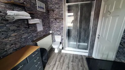 a bathroom with a toilet and a stone wall at Leecliff Guest House in Blackpool