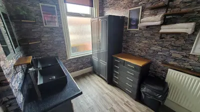 a bathroom with a sink and a stone wall at Leecliff Guest House in Blackpool