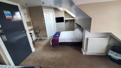 a small room with a bed and a staircase at Leecliff Guest House in Blackpool
