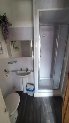 a bathroom with a shower and a toilet and a sink at Leecliff Guest House in Blackpool
