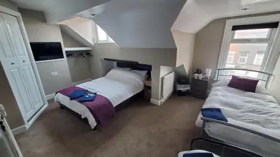 a bedroom with two beds and two windows at Leecliff Guest House in Blackpool