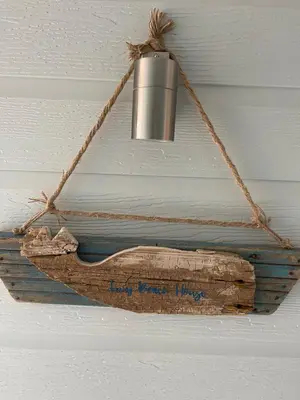 a light hanging from a ceiling with a wooden sign at Tiny Beach House in Saint Annes on the Sea