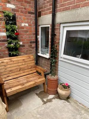 a wooden bench sitting next to a brick building at Tiny Beach House in Saint Annes on the Sea