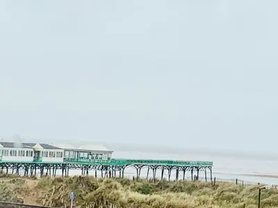 a pier on the beach with the ocean in the background at Tiny Beach House in Saint Annes on the Sea