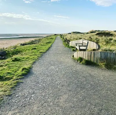 a dirt road next to a beach with a fence at KINGDOM HOLIDAY PARK - Parrot in Millom