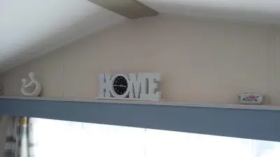 a shelf with a clock and a sign that reads home at KINGDOM HOLIDAY PARK - Parrot in Millom